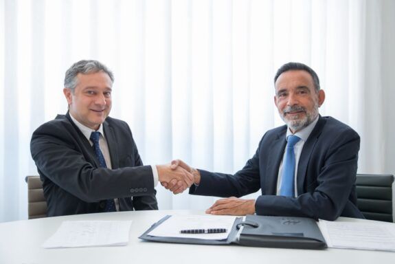 Business partners shaking hands over documents at an office table