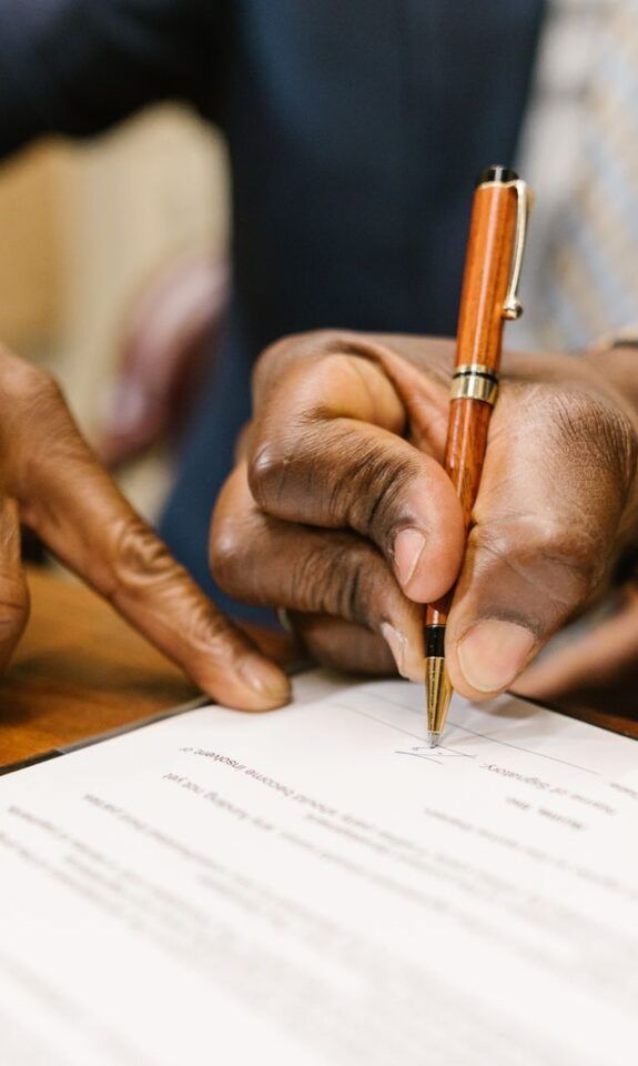 Close-up of a person writing on a business contract