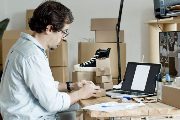 Ecommerce seller preparing packages for shipment at his desk