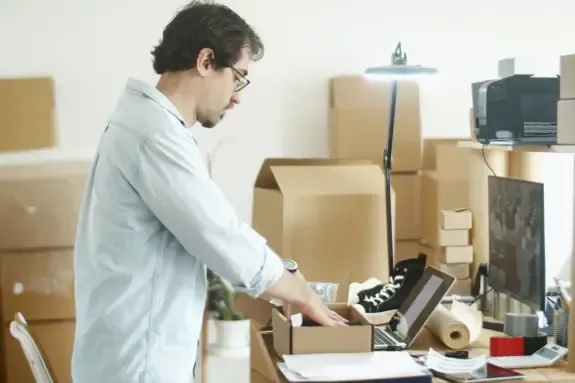 Brand owner packing products in a home office stocked with boxes