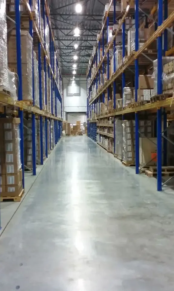 Long warehouse aisle with racks of packed cartons, the kind of inventory owners review before they sell an Amazon FBA business