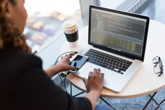 Developer working on a laptop with a smartphone and coffee on the table