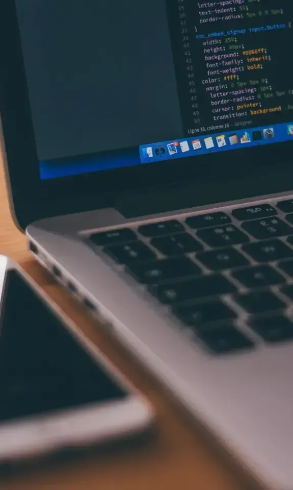 Laptop and smartphone side by side on a wooden desk