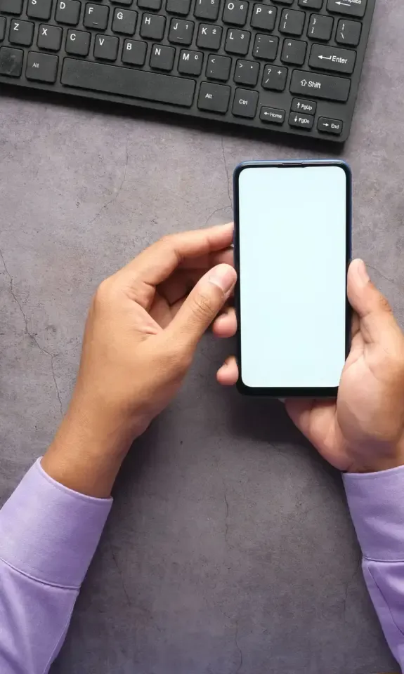 App founder holding a smartphone at a desk, ready to sell my app to the right buyer