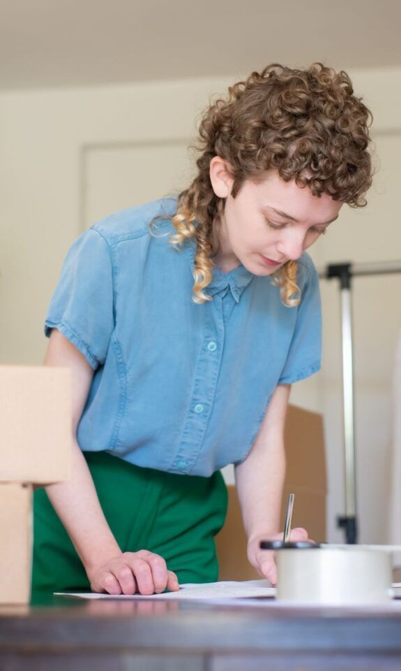 Ecommerce business owner packing online store orders next to a laptop