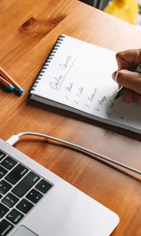 Business owner writing exit planning notes next to a laptop