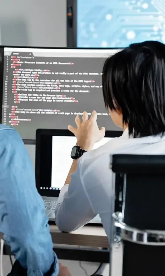 Two engineers working side by side at monitors in a software office