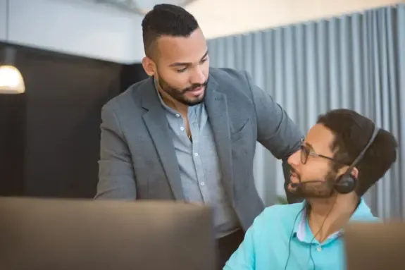 Two colleagues discussing an acquisition at an office desk